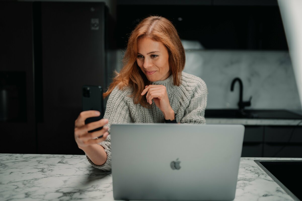 Women smiling at phone behind laptop